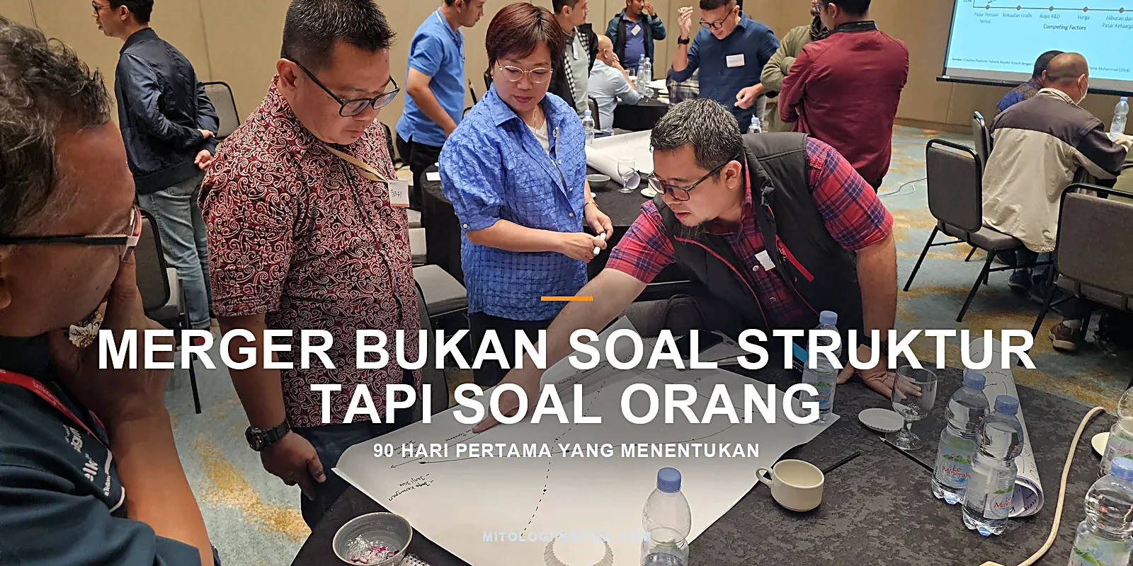Dua orang membaca rencana kerja bersama di meja, menggambarkan keselarasan arah dan peran di organisasi