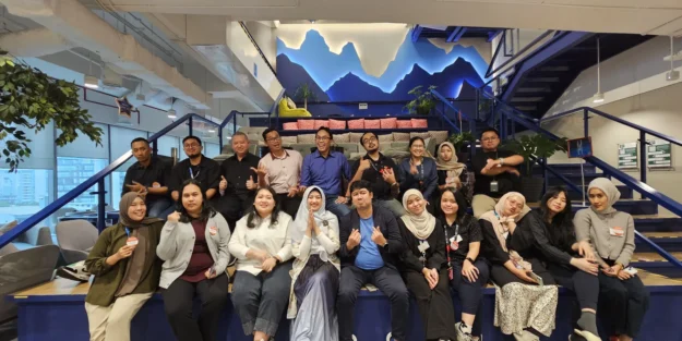Karyawan berfoto bersama seusai sesi team development di kantor, menunjukkan kerja sama tim yang bertahan