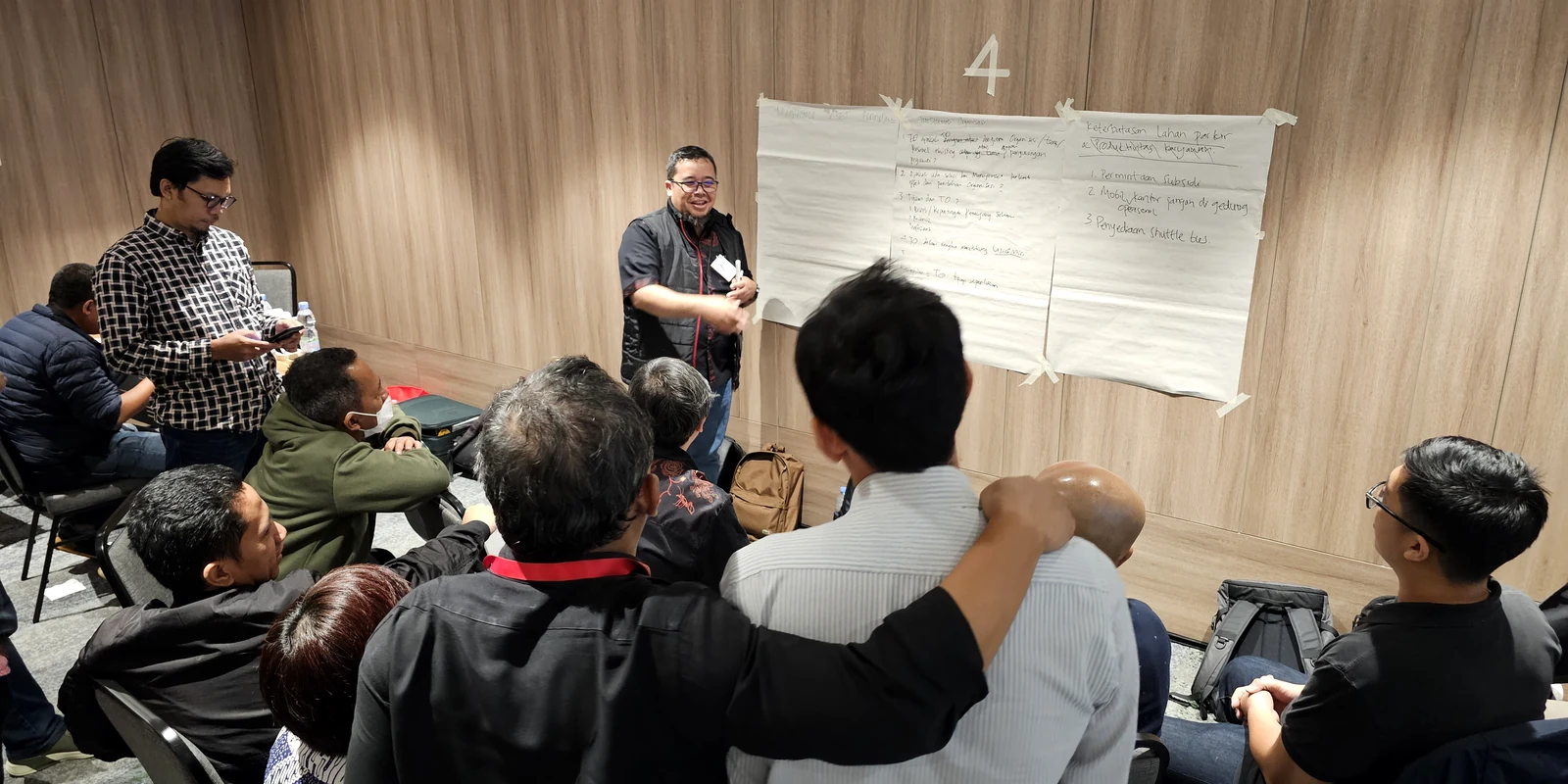 Peserta workshop berdiskusi di depan lembar kerja yang ditempel di dinding